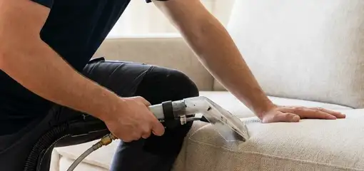 Professional upholstery cleaner deep-cleaning a fabric sofa with a handheld extraction tool, Birmingham, AL.